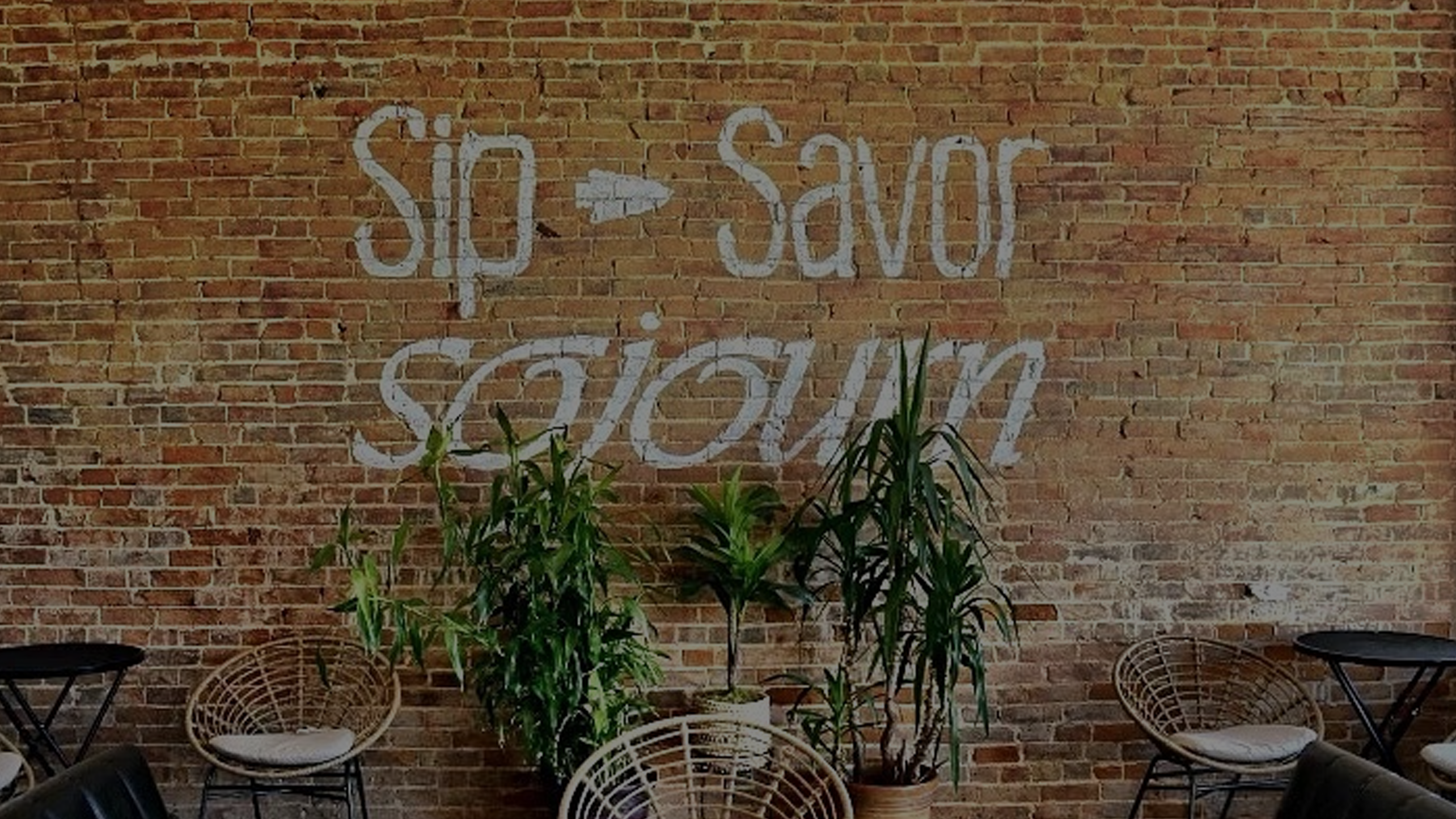 Sip Savor Sojourn on the brick wall at Rapp's Barren Brewing Company in Mountain Home, Arkansas, darkened for a website header image.